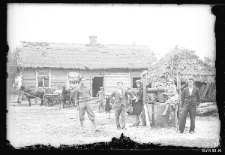 Grupa ludzi przed drewnianym domem