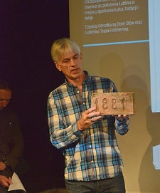 Dariusz Prażmo prezentuje cegłę z sygnaturą "1881"