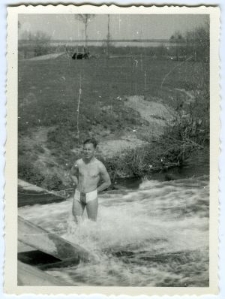 Mężczyzna stojący w rzece przy moście