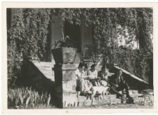 Młodzi ludzie siedący na schodach od strony ogrodu w Guzówce