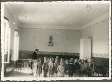 Dzieci z ochronki nr 2 w Lublinie ustawione w kółeczku w sali z dużym piecem
