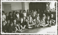 Dzieci z ochronki nr 6 w Lublinie pozujące do zdjęcia siedząc na ławie i podłodze